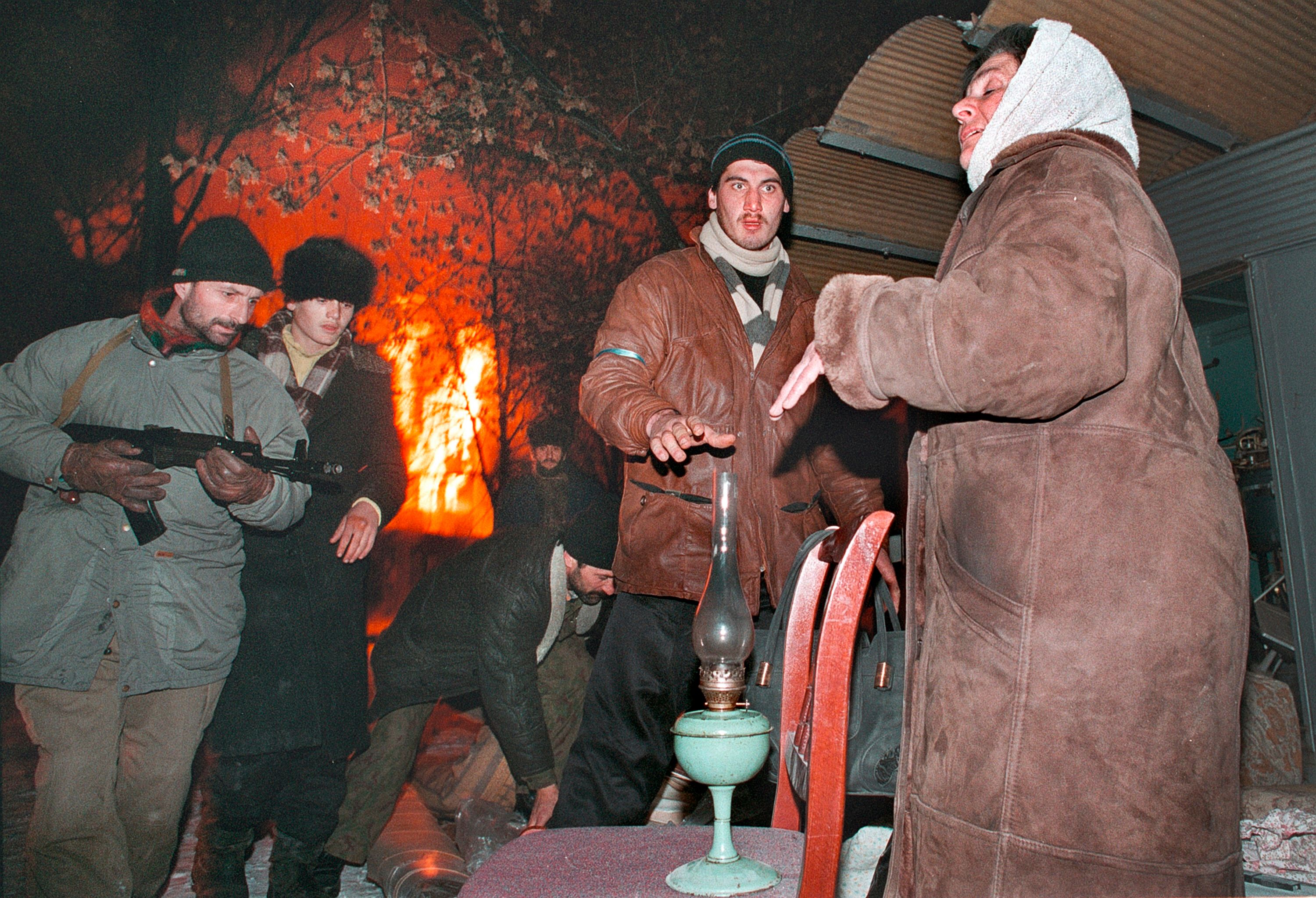 Боевики помогают женщине, которая покидает горящий Грозный. Декабрь 1994. Фото: Александр Неменов 